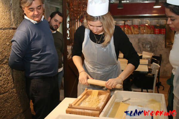 Colleagues making fresh pasta by hand at a work table
