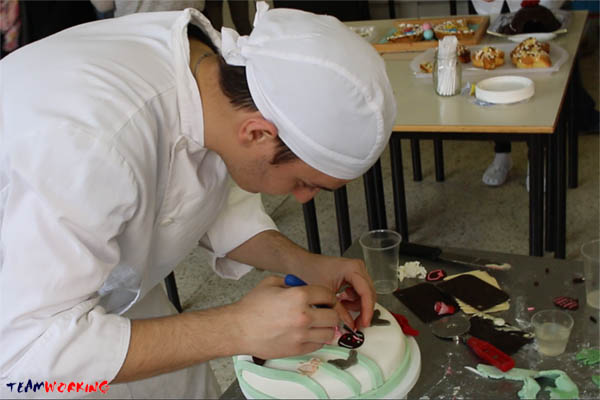 A team decorating a cake with sugar paste during a Cake Design activity