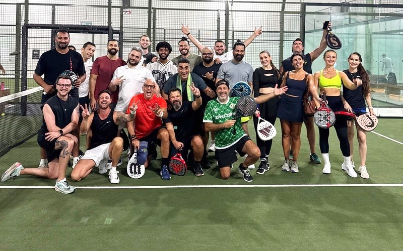 Teams on a padel court with a coach watching from the side