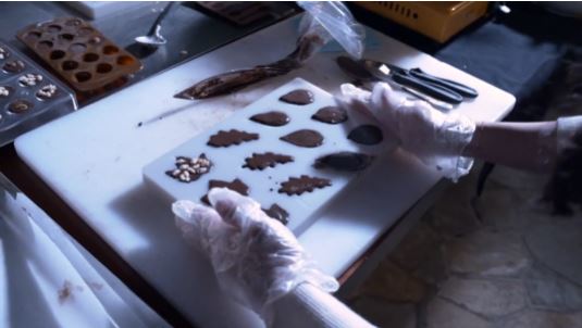 Hands shaping and decorating chocolates during a Choco Making activity
