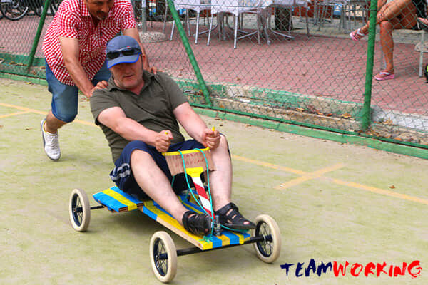 A mini car built from salvaged materials, on the track with its team