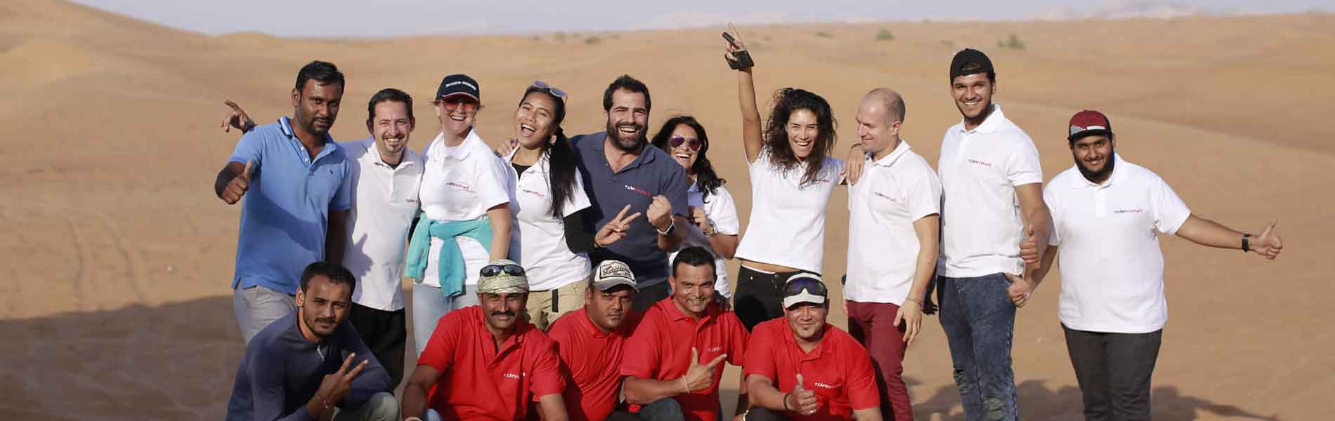 A large mixed group in the desert, in TeamWorking shirts, at the end of the day