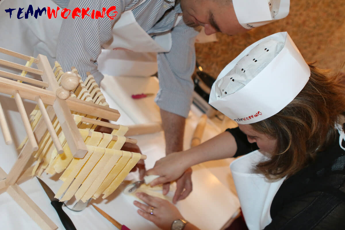 Colleagues making fresh pasta by hand at a work table