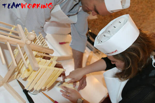 Colleagues making fresh pasta by hand at a work table