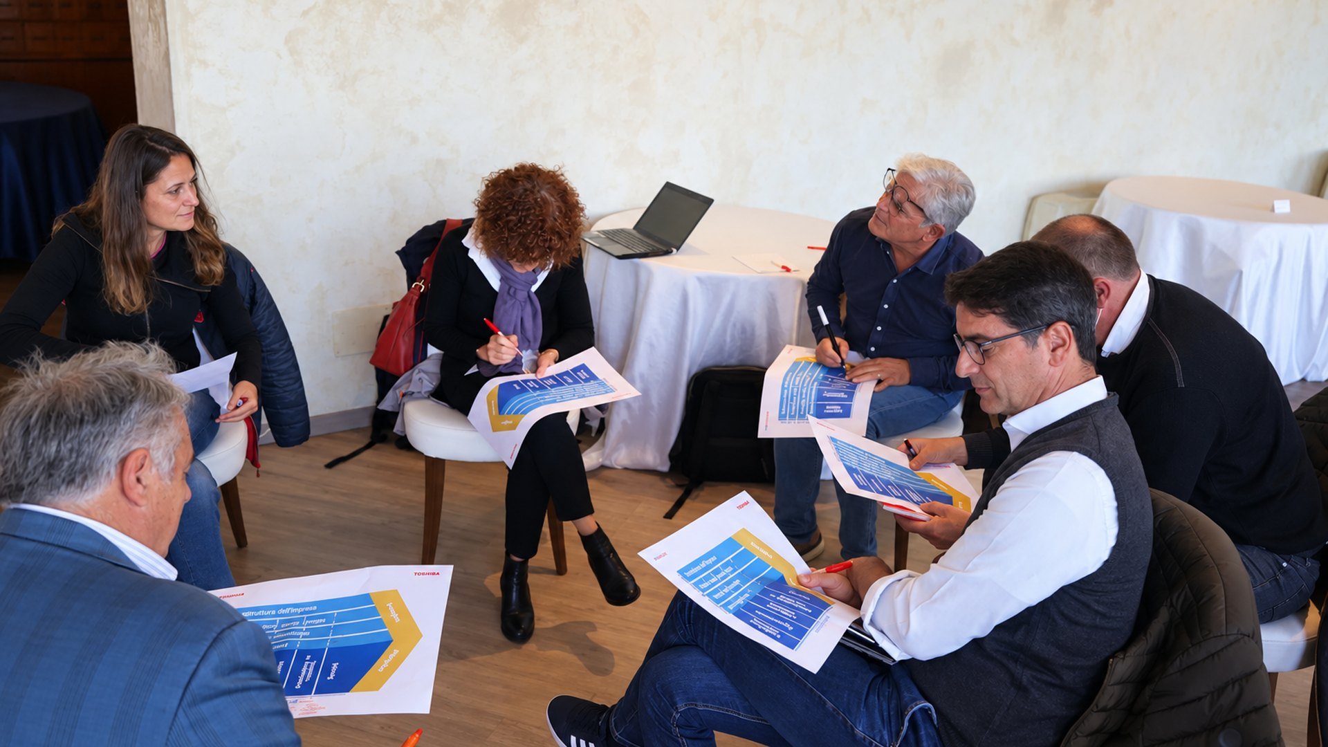 A team working on the value-chain handouts in a circle during a coaching session