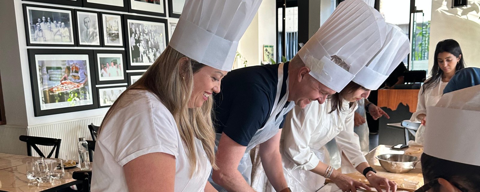 A team in chef hats working the dough side by side along a long table in Dubai